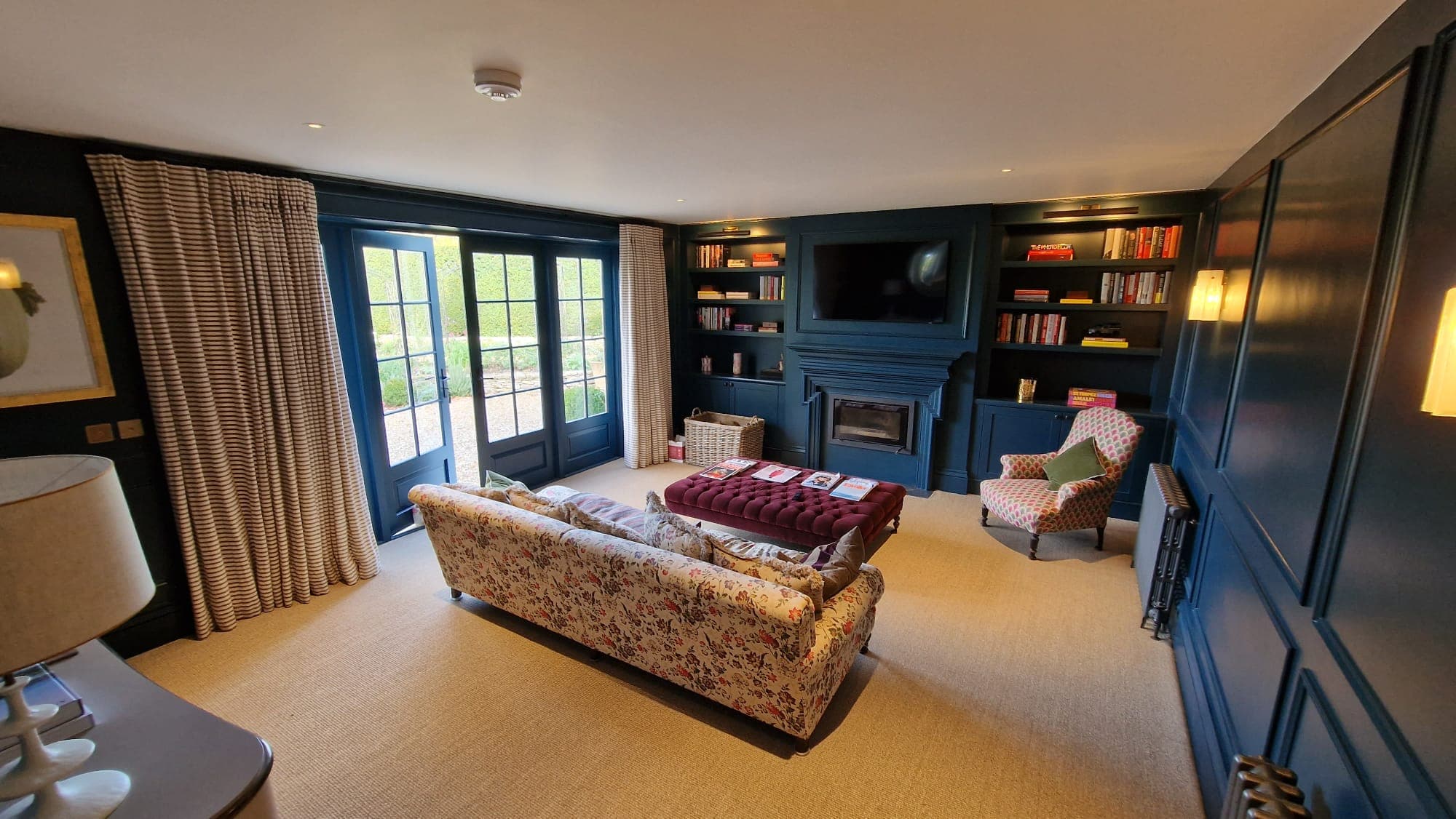 Living room after painting and decorating, with navy painted wall panelling and built-in bookshelves