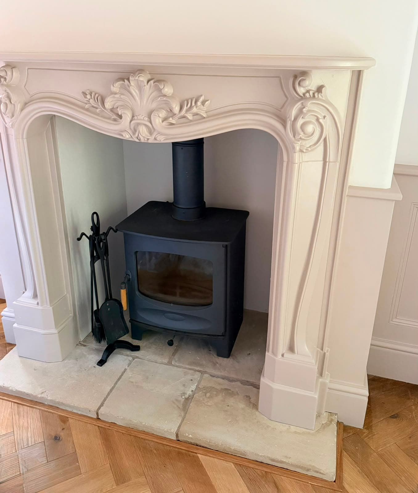Indoor refurbishment: a cream fireplace surround framing a black wood-burning stove on a stone hearth.