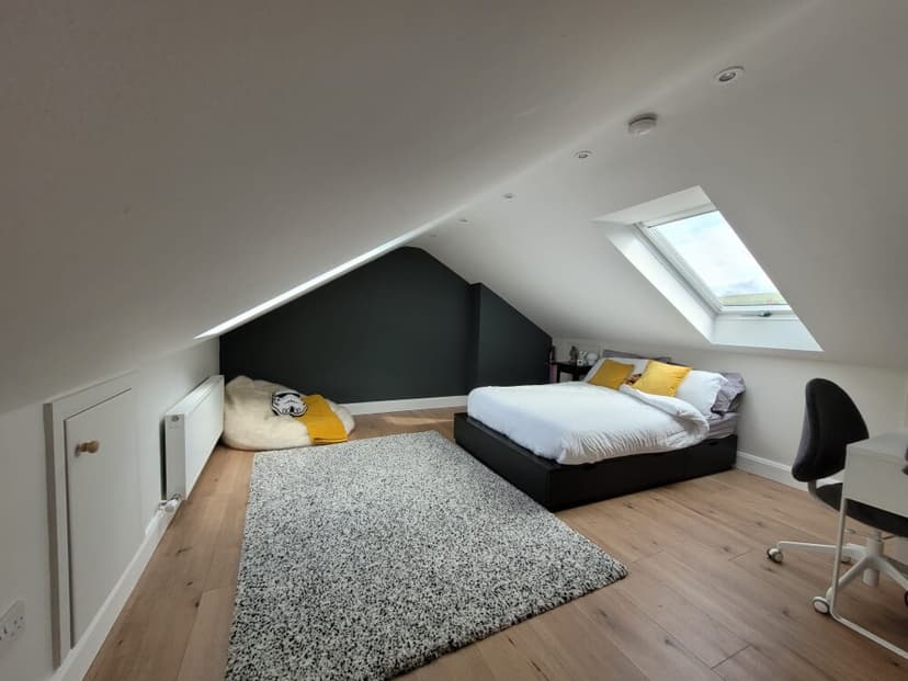 Finished loft room with a sloping ceiling, roof window and dark feature wall