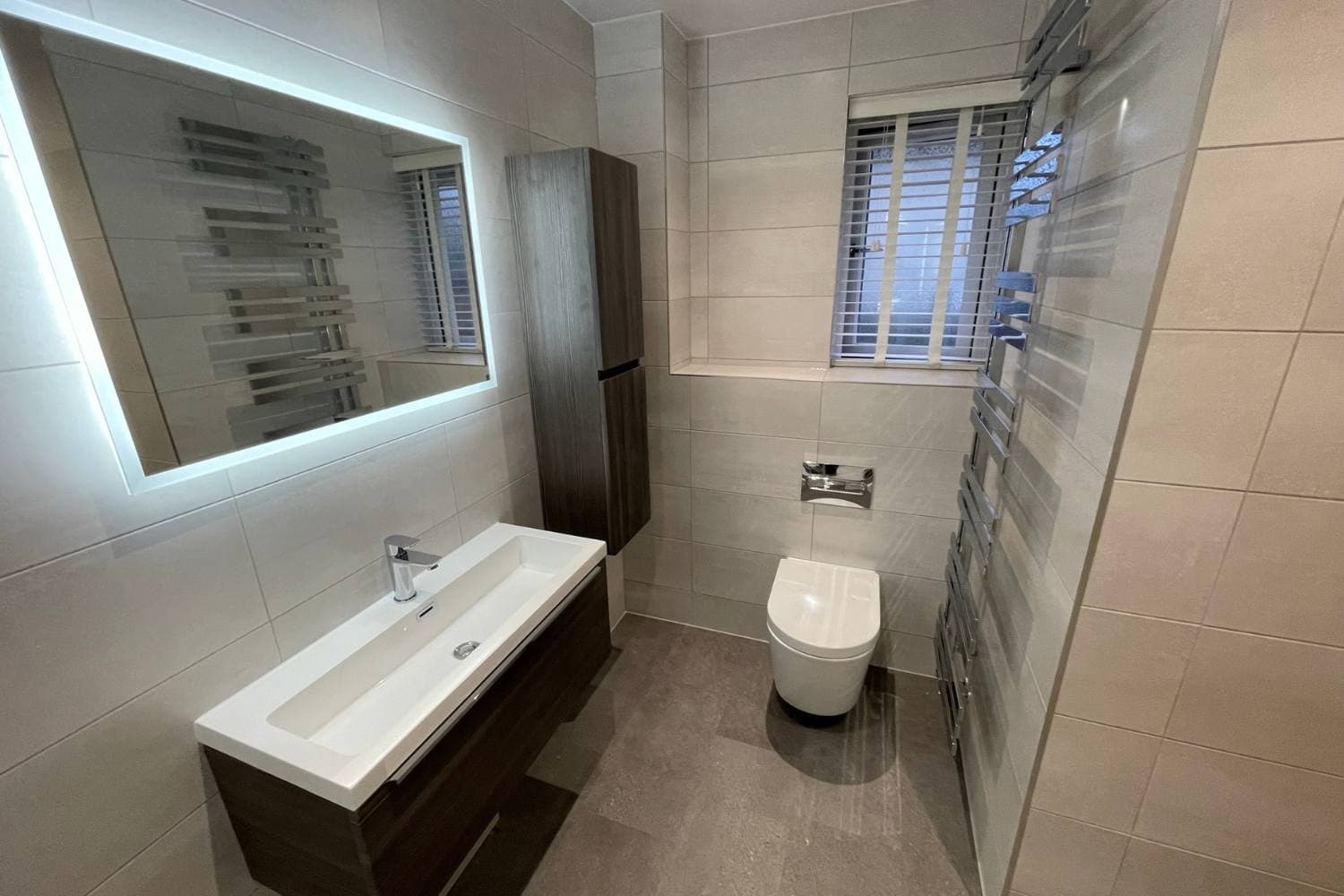 Bathroom vanity, basin and toilet in a tiled room, from Alpha Renovations Ltd's gallery