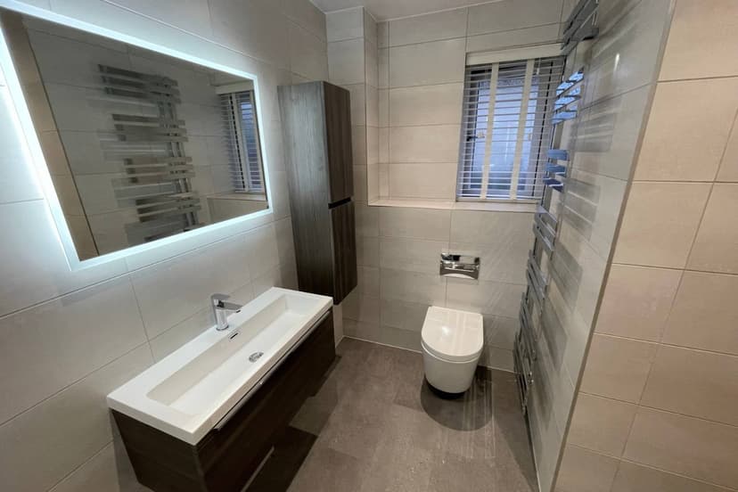 Tiled bathroom with illuminated mirror and vanity from Alpha Renovations’ website